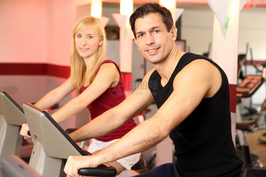 迷人的女人和男人在健身房骑自行车有氧运动身体成年人运动运动服训练女性健身家庭俱乐部图片