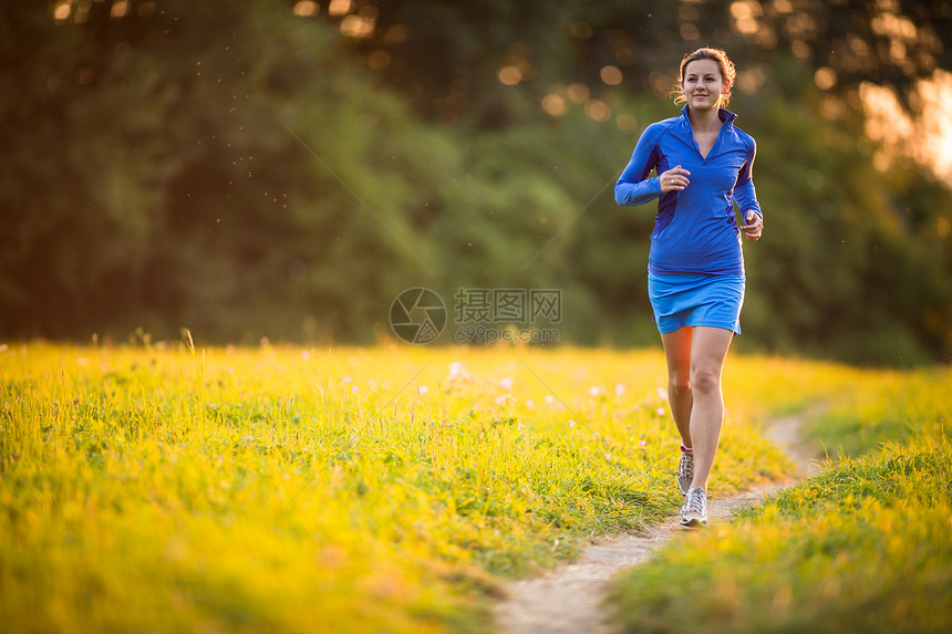 年轻女子在阳光明媚的夏日夜晚户外奔跑越野女士慢跑者慢跑活力跑步草地火车寒冷城市图片