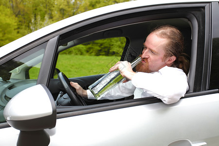 酒醉男人在车里喝着酒瓶酒运输男性瓶子司机汽车注意力监狱罪犯速度酒精孤独高清图片素材