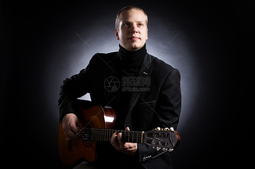 穿黑西装的年轻音乐家拿着吉他娱乐岩石演员男人套装男性音乐会乐器独奏星星图片