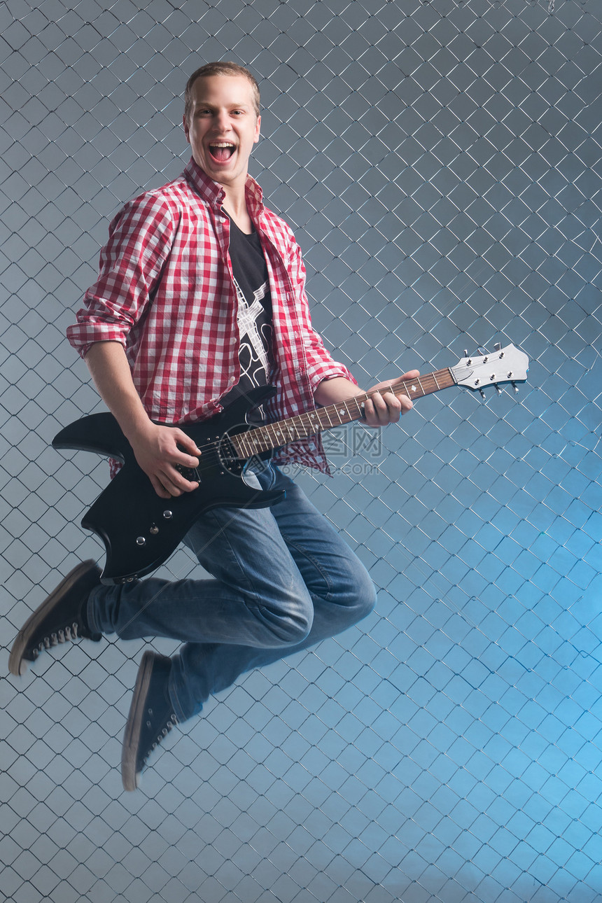 音乐 年轻的音乐家 有一把吉他在空中男性衬衫空气演员牛仔裤旋律男人栅栏摇杆岩石图片
