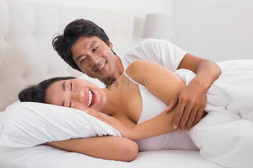 躺在床上微笑的情侣快乐女性公寓感情家庭夫妻住所羽绒被枕头男性图片