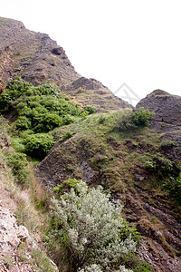 山蓝色爬坡石头天空阴影绿色植物岩石灰色衬套背景图片
