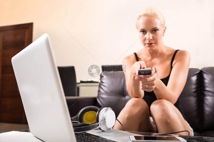 带遥控的金发女孩女士手机享受日常生活喜悦电影电视沙发电脑频道图片