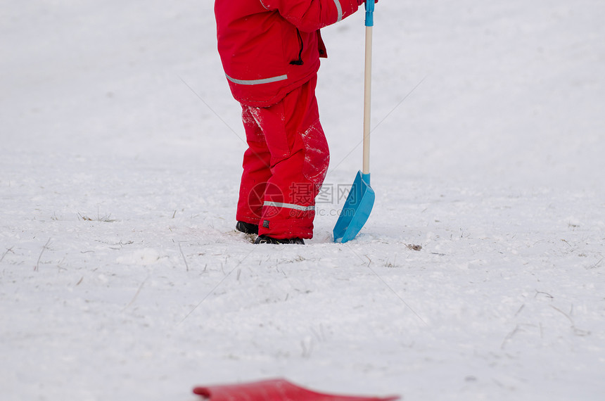 孩子穿着防水衣 拿着雪铲子站着图片