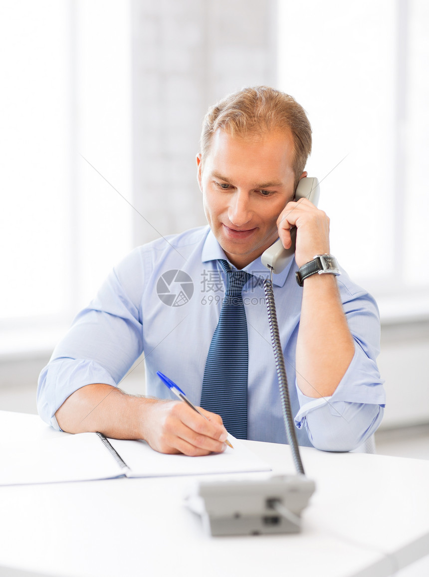 英俊的商务人士在电话里聊天秘书笔记本工作男性热线写作微笑男人企业家会计图片