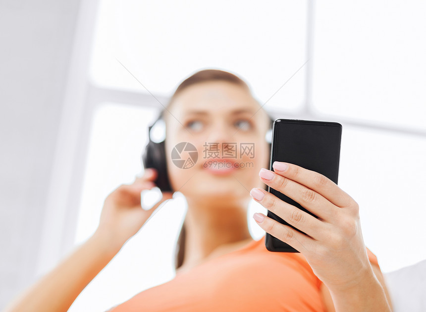 家中有耳机和智能手机的妇女店铺互联网女孩冲浪享受音乐播放器玩家女性立体声歌曲图片