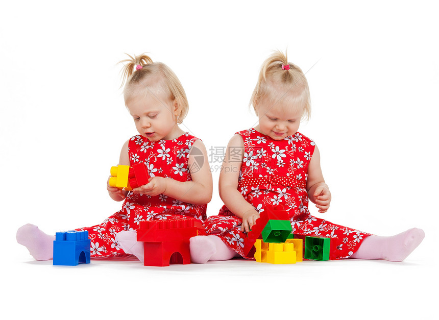 两个身穿红裙子的双胞胎女孩 玩砖块游戏女孩们立方体兄弟姐妹婴儿幼儿连衣裙乐趣积木孩子们地面图片