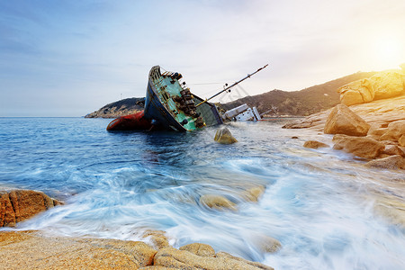 海难和海景日落沉船支撑货物海岸线钓鱼商品岩石血管海滩海岸背景图片