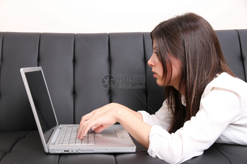 西班牙裔年轻女子在沙发上冲浪皮革互联网女性女孩青少年电脑说谎牙裔女士休息图片