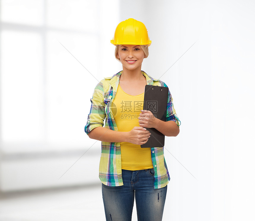 带着剪贴板戴头盔的笑着女人房间安全帽职业工人建设者安全工作维修专家承包商图片