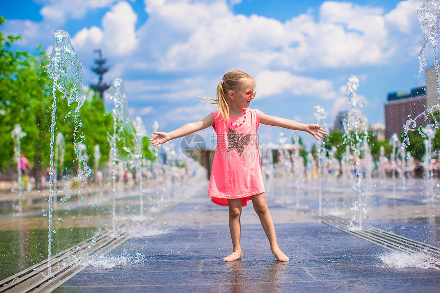 快乐的小女孩在阳光明媚的日子 在露天街头喷泉玩反射飞溅时间溪流太阳喜悦女性婴儿乐趣微笑图片