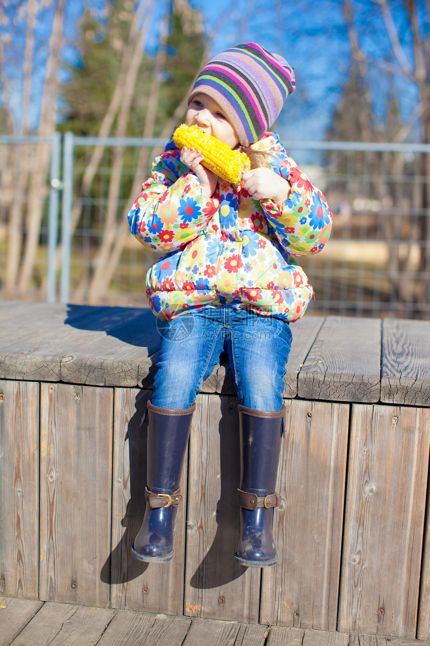 可爱的小可爱女孩 在公园户外吃玉米孩子蔬菜植物帽子女性粮食种子童年午餐烹饪图片