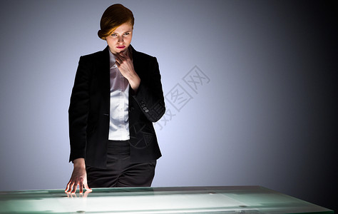 红头女商务人士站在一个办公桌旁思考女士商业红发女性人士职业公司专注桌子商务背景图片