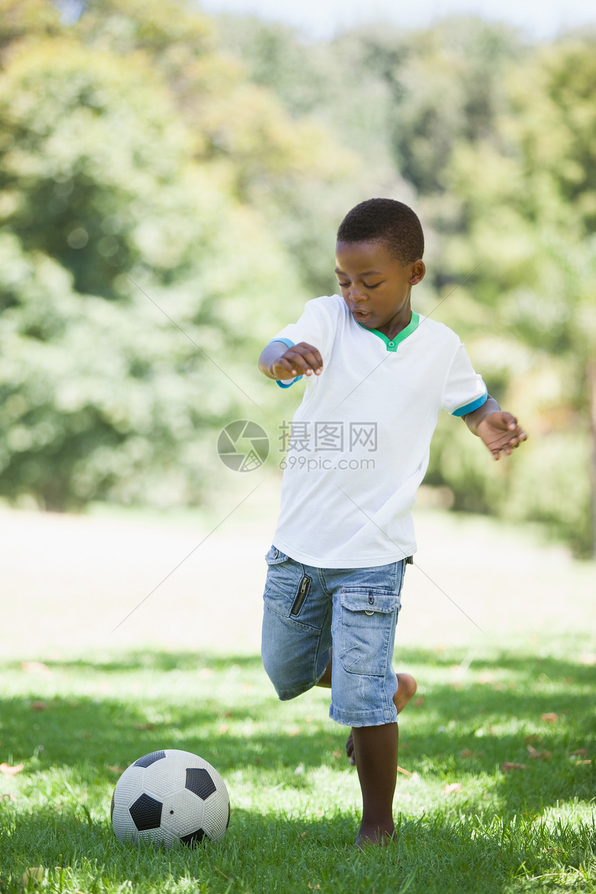 小男孩踢橄榄球 在公园踢足球图片