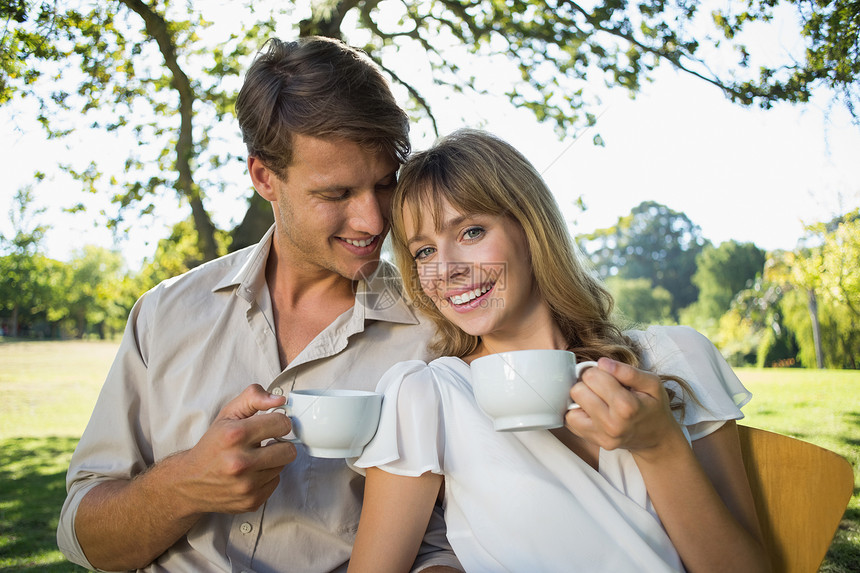 在咖啡馆外面喝茶的一对微笑的情侣图片