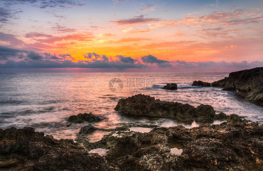 日落时落的洛基海滩海浪旅行地平线石头海洋天空橙子日落海岸反射图片