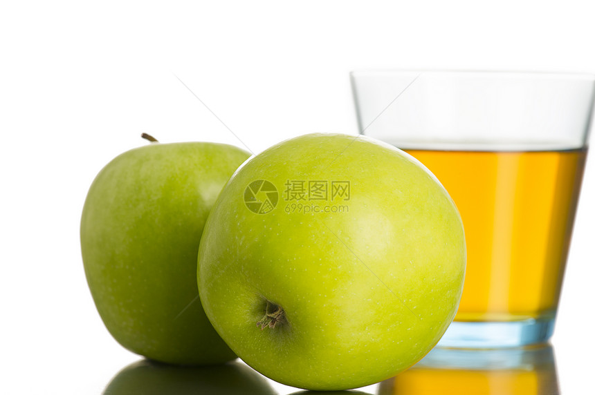 在一杯苹果汁旁边的两个绿苹果图片