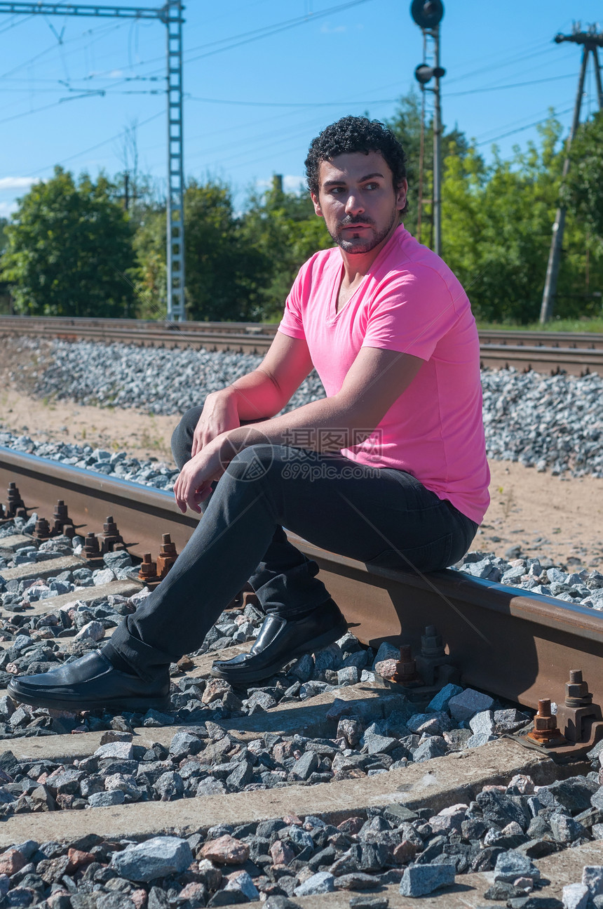 坐在铁轨上的年轻男子太阳铁路数字工业火车成人男性潮人粉色金属图片