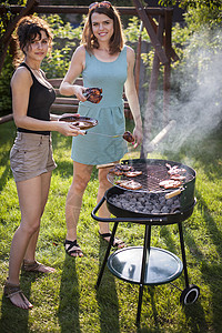 两个漂亮女孩在烤架上做饭烹饪女孩野餐香肠黑色女性花园烤串饮食牛肉背景图片