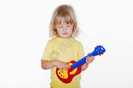 带着玩具吉他男孩吉他男性孩子音乐乐器金发头发白色背景图片