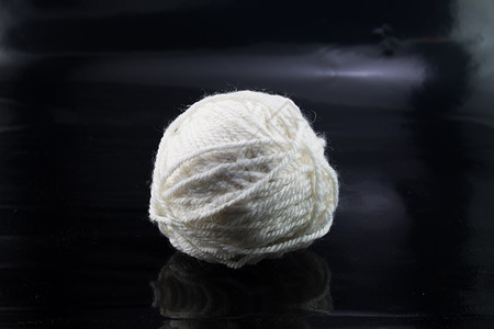 黑色背景上的白羊毛线球羊毛纺织品工艺圆形艺术背景图片