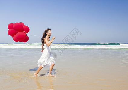 海滩女孩红气球红气球女孩海滩青年喜悦乐趣微笑天空女士享受幸福假期背景