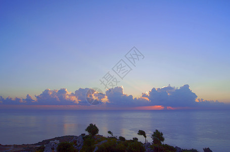 地中海上空的太阳升起植物石头海岸天空地平线背景图片