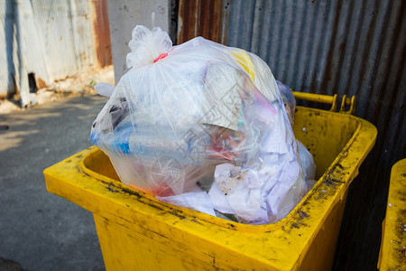 你是个什么垃圾泰国人行道上满是垃圾的黄色垃圾桶背景