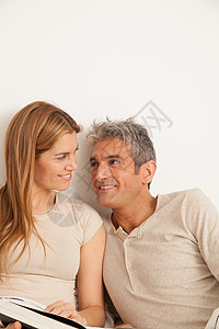 快乐的一对情侣观看相片专辑男人微笑乐趣女性卧室阅读夫妻房子财产婚姻背景图片
