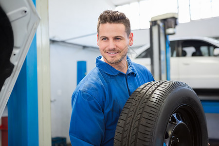 手持轮胎轮机的机械师蓝色工程师服务汽车男性男人作坊微笑修理工作服蓝色的高清图片素材