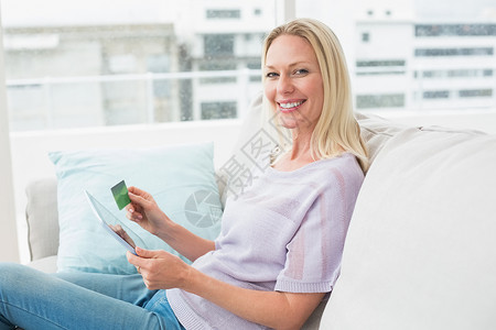 在沙发上戴数字牌片和信用卡的快乐妇女背景图片