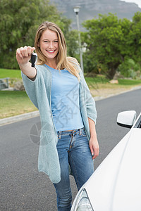 年轻女性握着钥匙手势女士零件车辆闲暇代理商快乐驾驶汽车微笑背景图片
