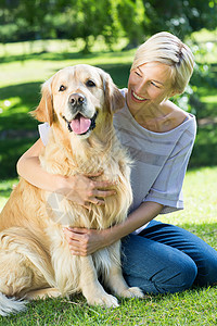 漂亮金毛在公园拥抱她的狗的金发快乐微笑家畜晴天闲暇宠物阳光女性农村金发女郎草地背景