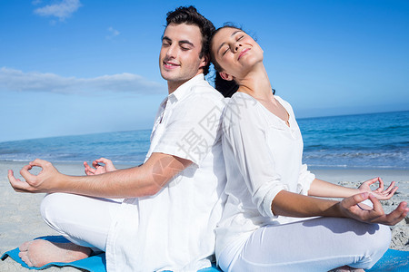 快乐的情侣在水边做瑜伽护理女性女士闲暇冥想微笑运动垫背靠背身体运动服背景图片