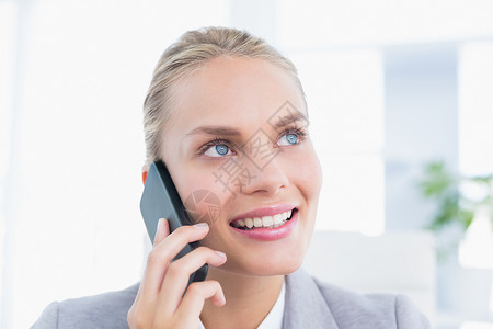 微笑的商务人士在她的办公桌上打电话女性职场商务沟通公司呼唤办公室电话快乐女士背景图片