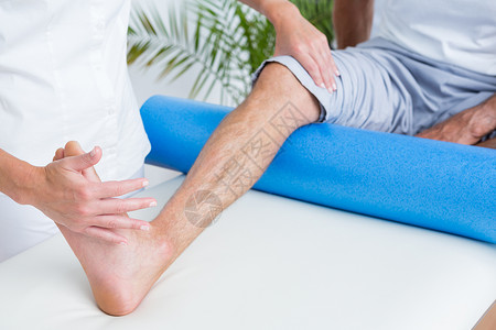 按摩垫医生检查她的病人腿治愈肌肉女性女士运动双手关节男性按摩治疗背景