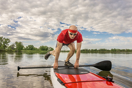 站在科罗拉多湖上划水晴天运动桨手立桨板红色娱乐绿色桨板男性肌肉背景图片