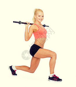 微笑着运动的女子用巴铃锻炼训练弓步力量肌肉女孩哑铃健身房培训师二头肌身体合身高清图片素材