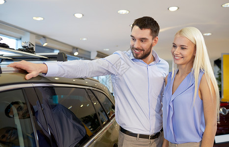 快乐的情侣在汽车展或沙龙买车男人女孩汽车拉丁顾客夫妻消费者车辆妻子销售背景图片