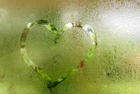 在蒸汽玻璃窗上的心水滴液体窗户玻璃宏观雨滴绿色背景图片