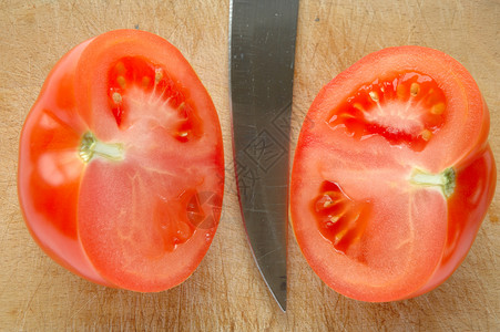 切面板上的番茄小吃厨房菜板食物蔬菜刀刃绿色白色红色木头背景图片