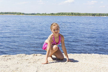 粉色女士的泳衣穿粉红色泳衣的可爱女孩在河岸上女士活动运动孩子金发女郎乐趣女性白色小学生女学生背景