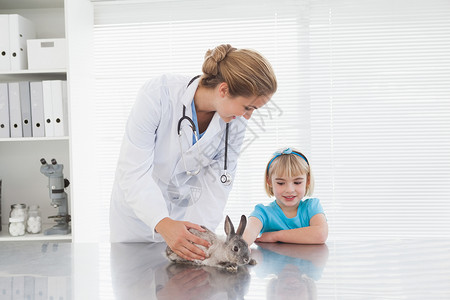 给一个年轻女孩看兔子的蔬菜孩子从业者头发宠物实验工作女性兽医动物医疗背景图片