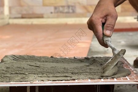 石膏砂浆地板瓷砖与瓷粘合物和纤维结合在一起水泥安装材料缺口砂浆石膏建设者修理工研磨工作背景