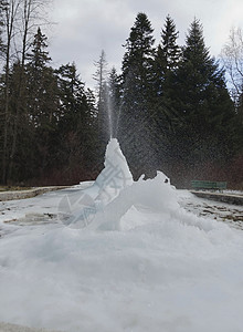 冬季的冰冻喷泉天空针叶树冰川绿色冰柱树木里拉白色背景图片