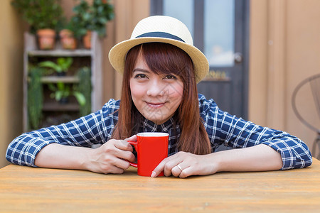 穿着帽子的女士坐在户外 喝热饮放松咖啡咖啡店女性女孩巧克力杯子饮料食物享受黑发脸高清图片素材