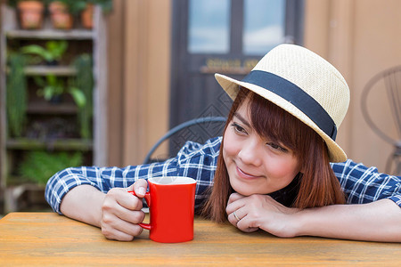 穿着帽子的女士坐在户外 喝热饮放松女性享受食物眼睛咖啡店咖啡饮料杯子女孩巧克力黑发高清图片素材