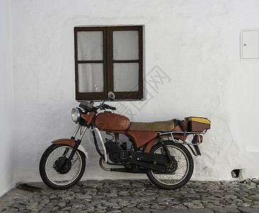 旧轻便摩托车或小型摩托车房子窗户白色街道石头排气玻璃背景图片