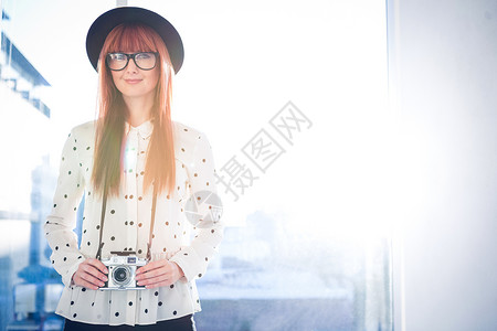 微笑的时髦女人的肖像快乐红发爱好女性休闲服装潮人刘海眼镜城市背景图片
